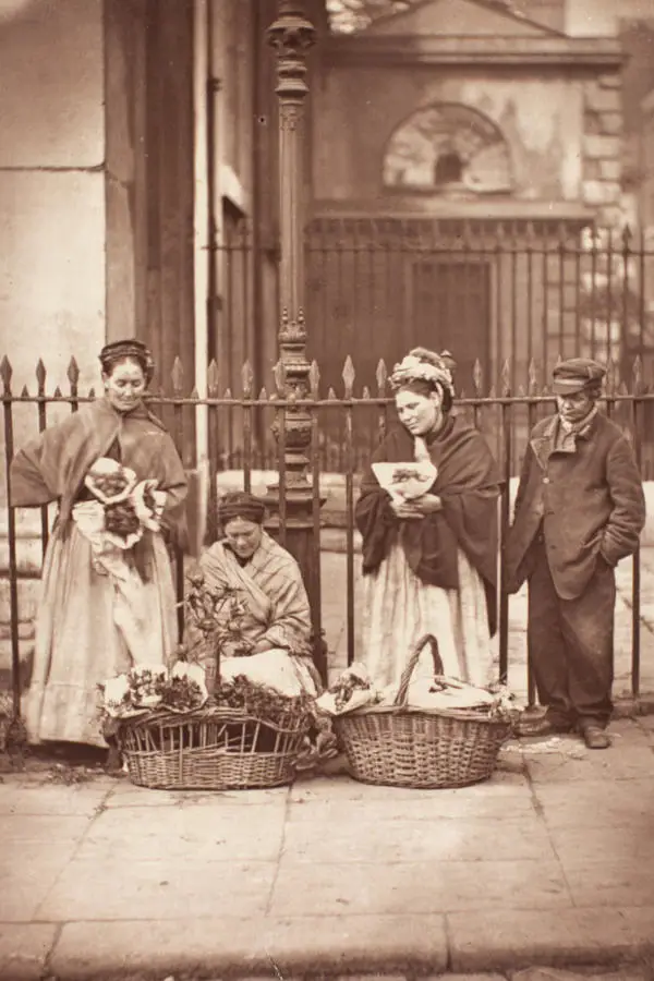 Covent Garden flower women selling flowers from baskets in from of some railings