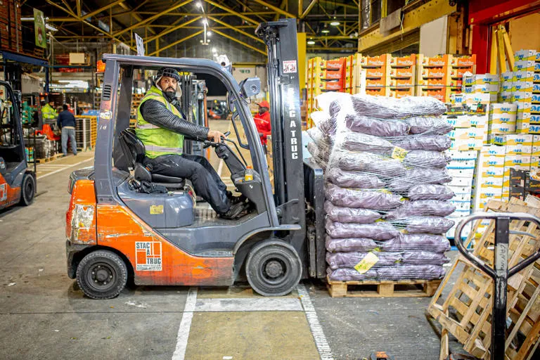 Forklift lifting pallet full of bags of produce