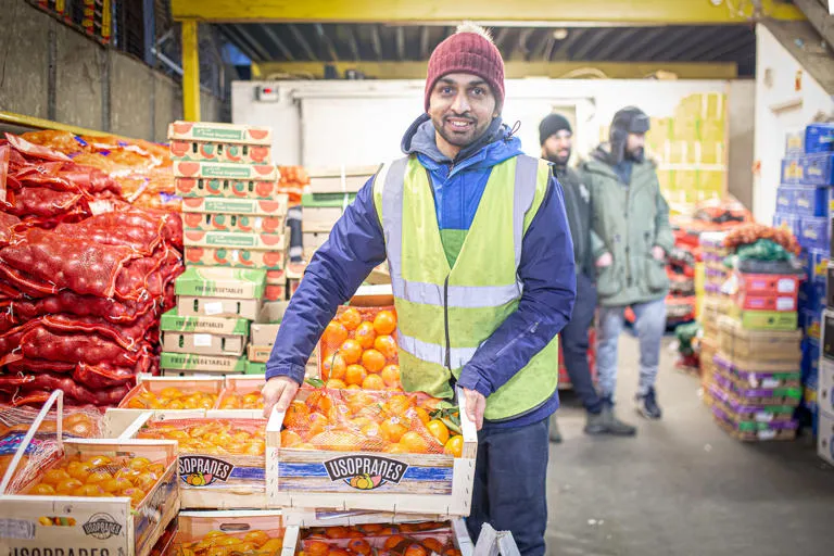 market operative holding box filled with oranges