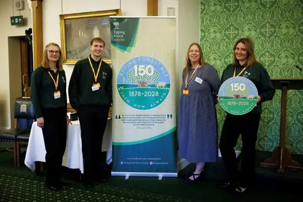 Four people stand by a sign celebrating the 150th anniversary of the Epping Forest Act at parliament last month