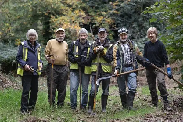 Volunteers in the forest with billhooks and tools.