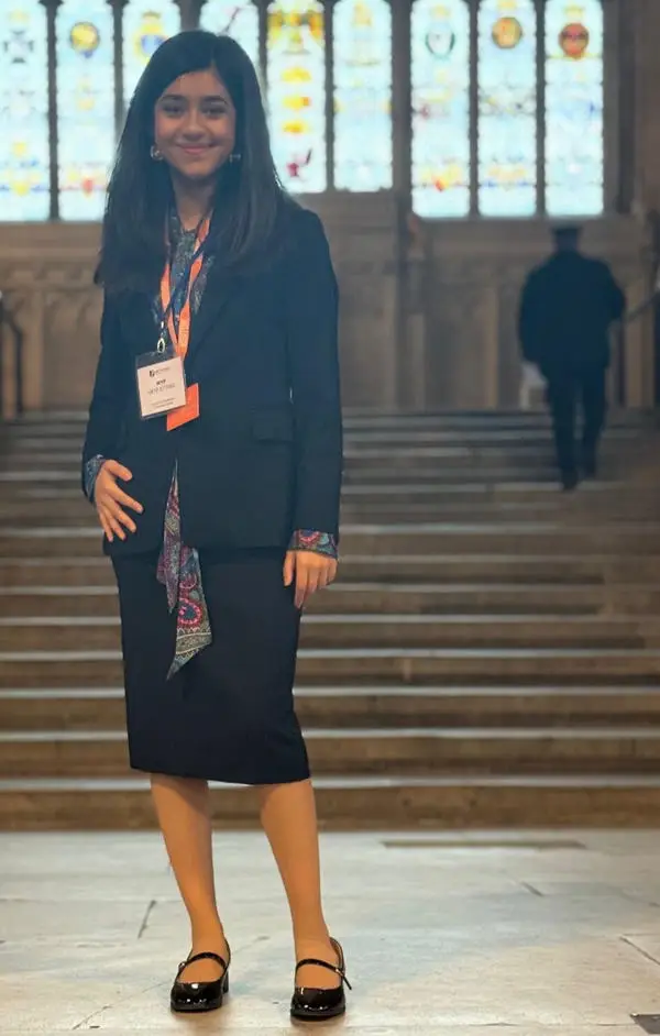 Youth Parliament member Zara standing on the steps inside Westminster Hall, with stained‑glass windows behind