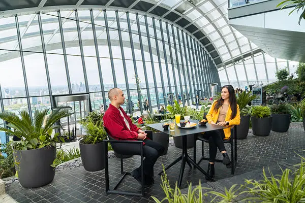 couple having breakfast at a glass-covered rooftop garden