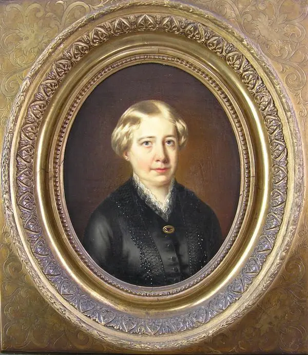 A head and shoulders portrait of a lady with short grey hair wearing a black Victorian period dress with black beading and white lace edging, decorated with an oval brooch.