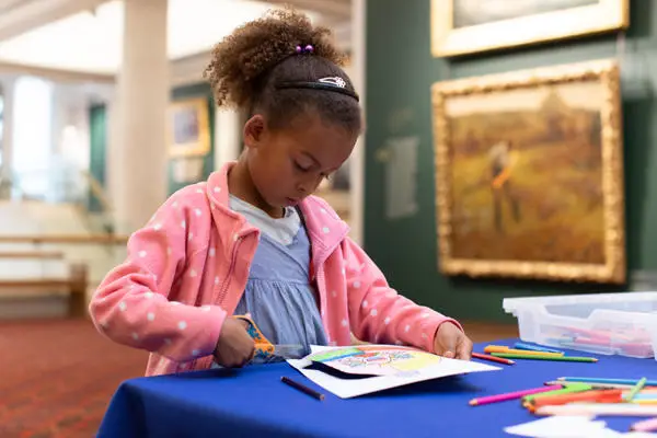 Girl colouring and cutting paper with scissors at Guildhall Art Gallery