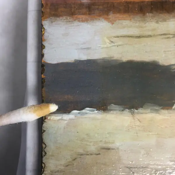 Close-up on varnish removal from painting with cotton swab