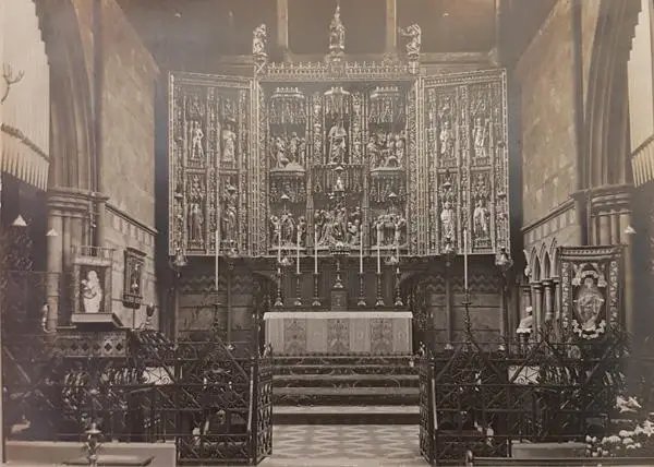 Interior of St Alban the Martyr, Holborn, showing the altar and six candlesticks surmounted by an elaborate reredos beyond an ornate iron choir screen with double gates