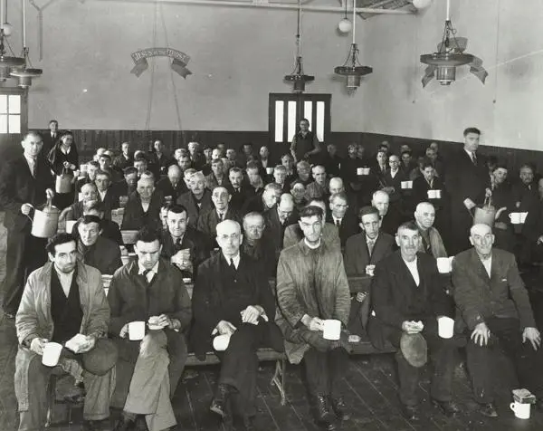 Men in a church hall with bread and a drink