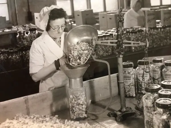 A lady filling up a jar of Clarnico perfection sweet drops