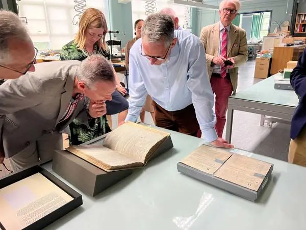 The tour group looking at iconic documents by Robert Hooke, Isaac Newton and John Harrison, in the Conservation Studio