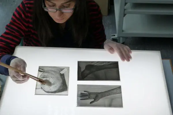 Staff member cleaning glass plate negatives